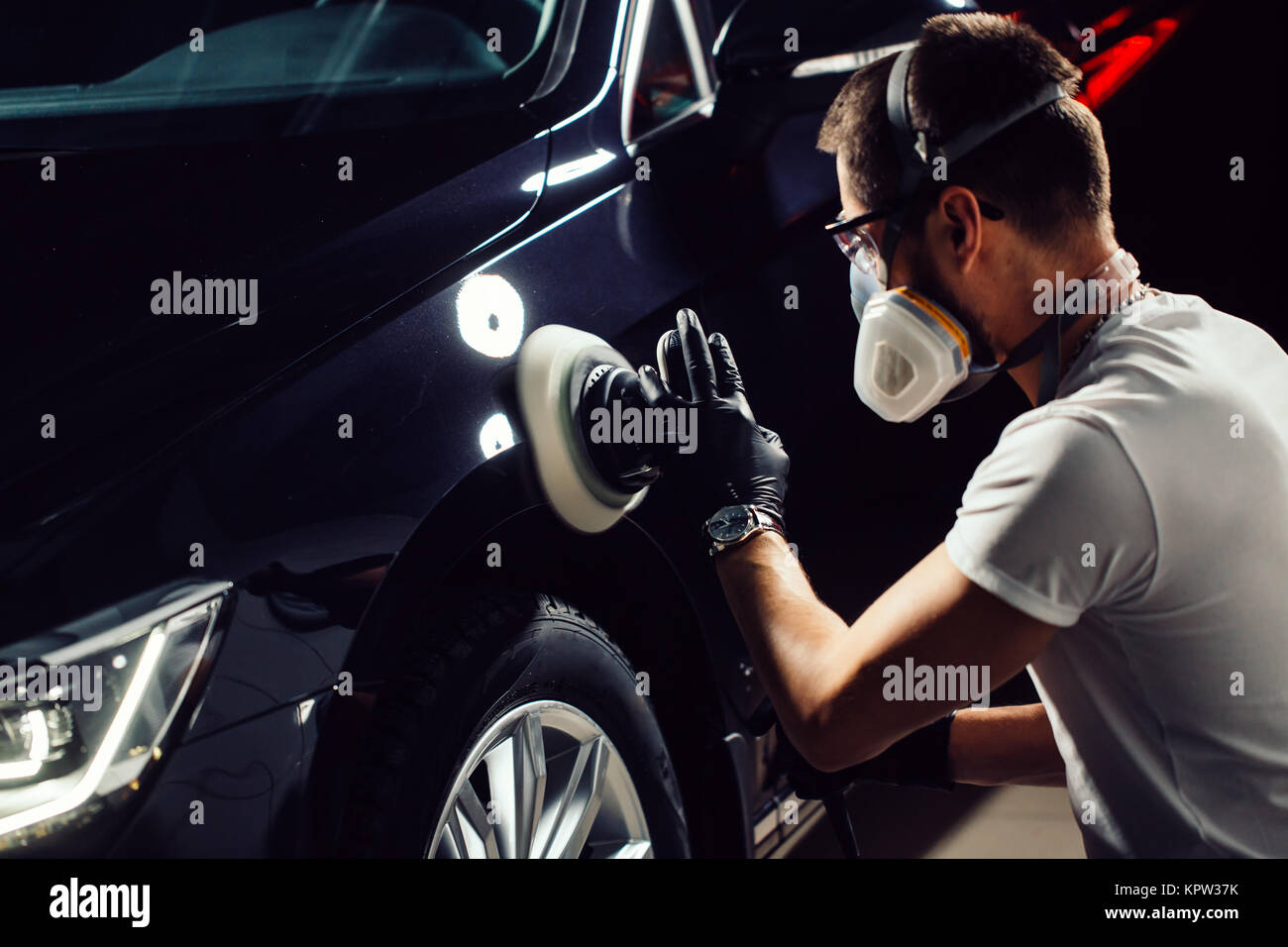 Car detailing man with orbital polisher in auto repair shop