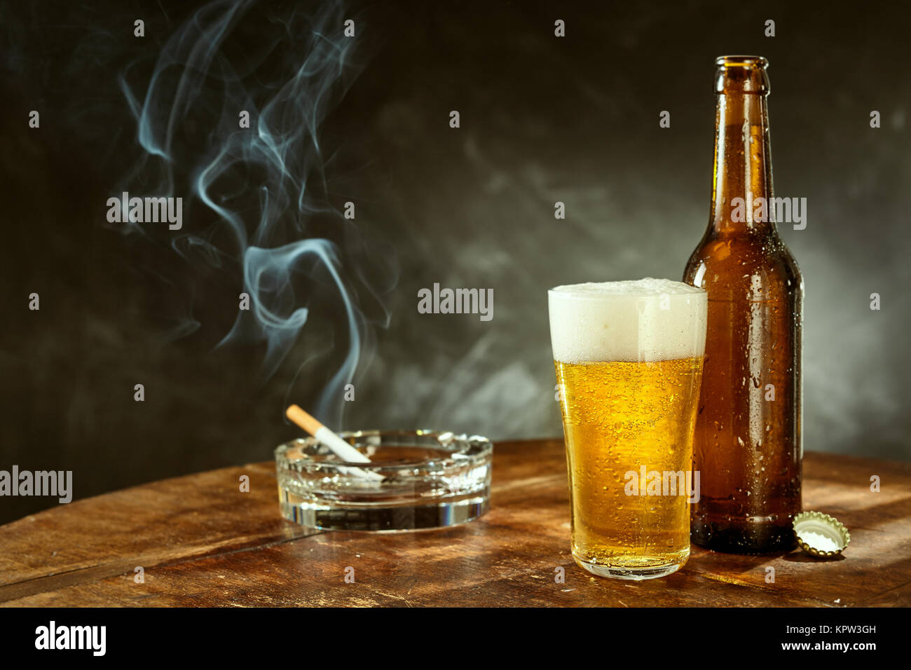 Burning cigarette in a glass ashtray and a long cold beer in a pint