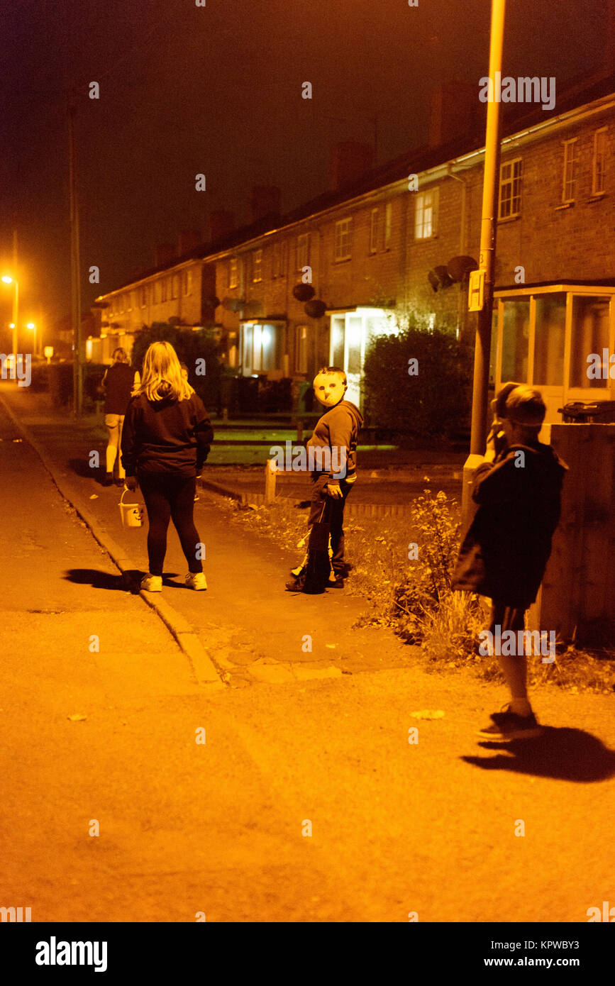 English kids at night going trick and treating wearing masks and Halloween costumes in Essex England Silver End Stock Photo