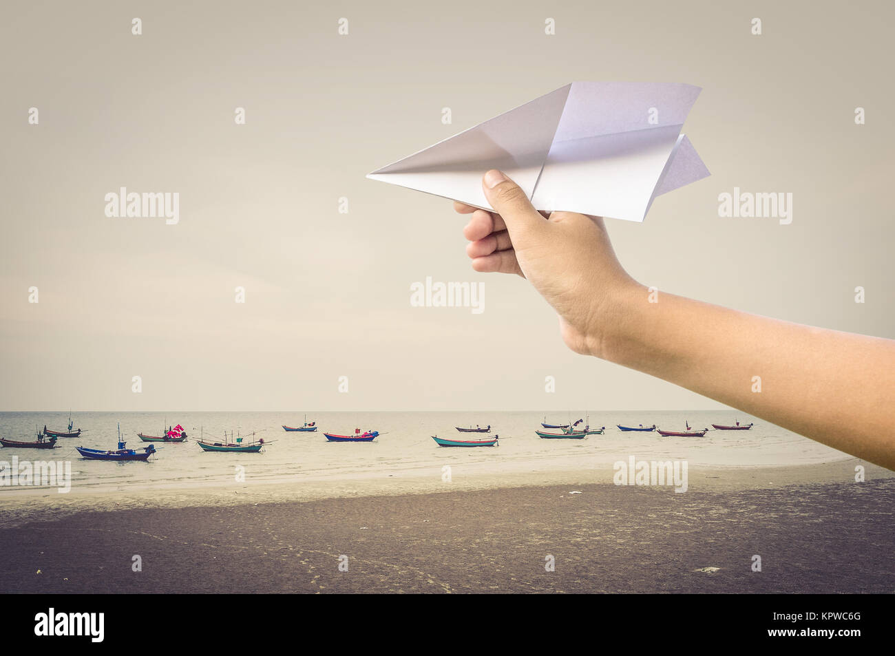 plane paper in children hand over sea and boats Stock Photo