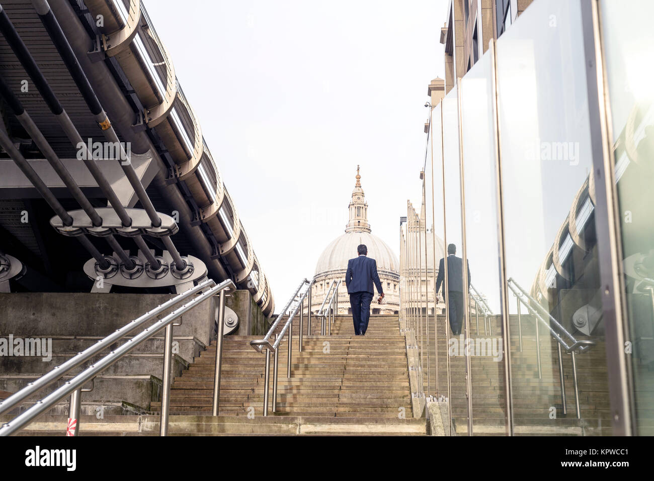 Man in business suit walking up steps towards St Paul’s Cathedral in London England Stock Photo