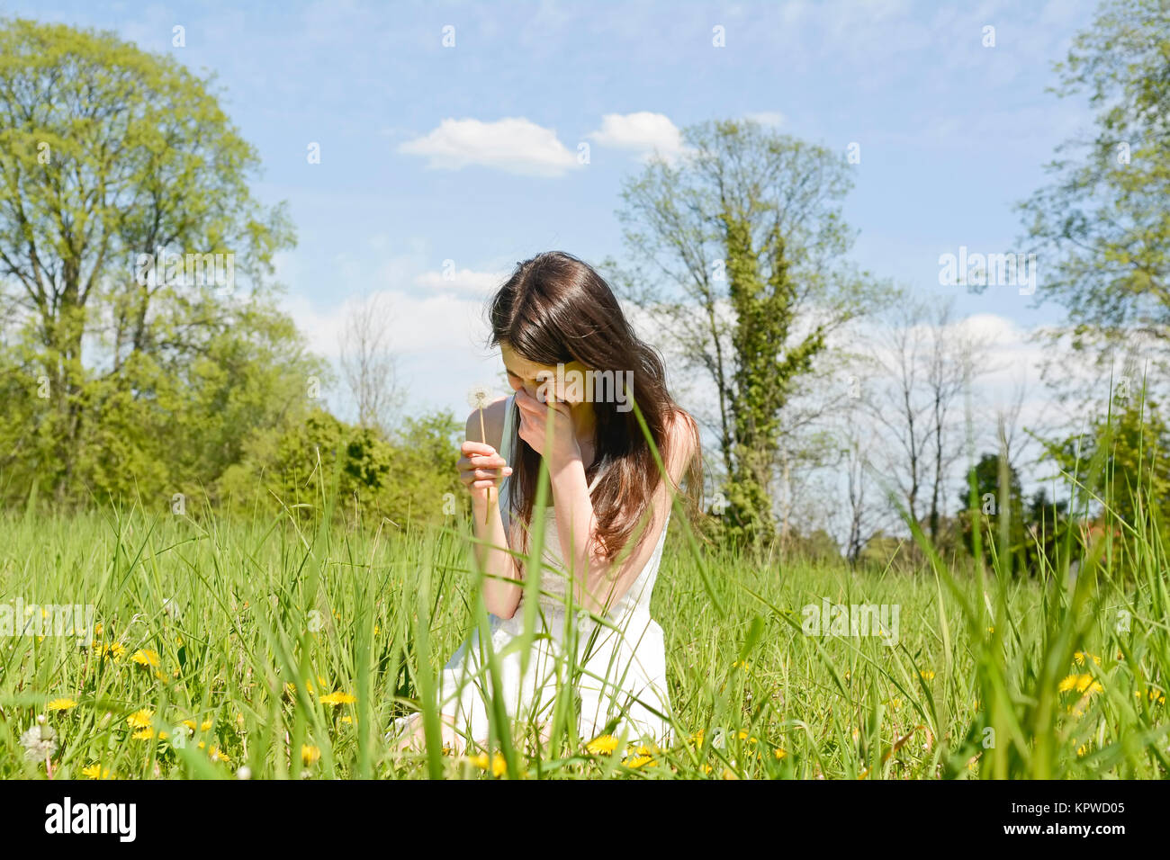 junge frau niest auf einer blumenwiese Stock Photo