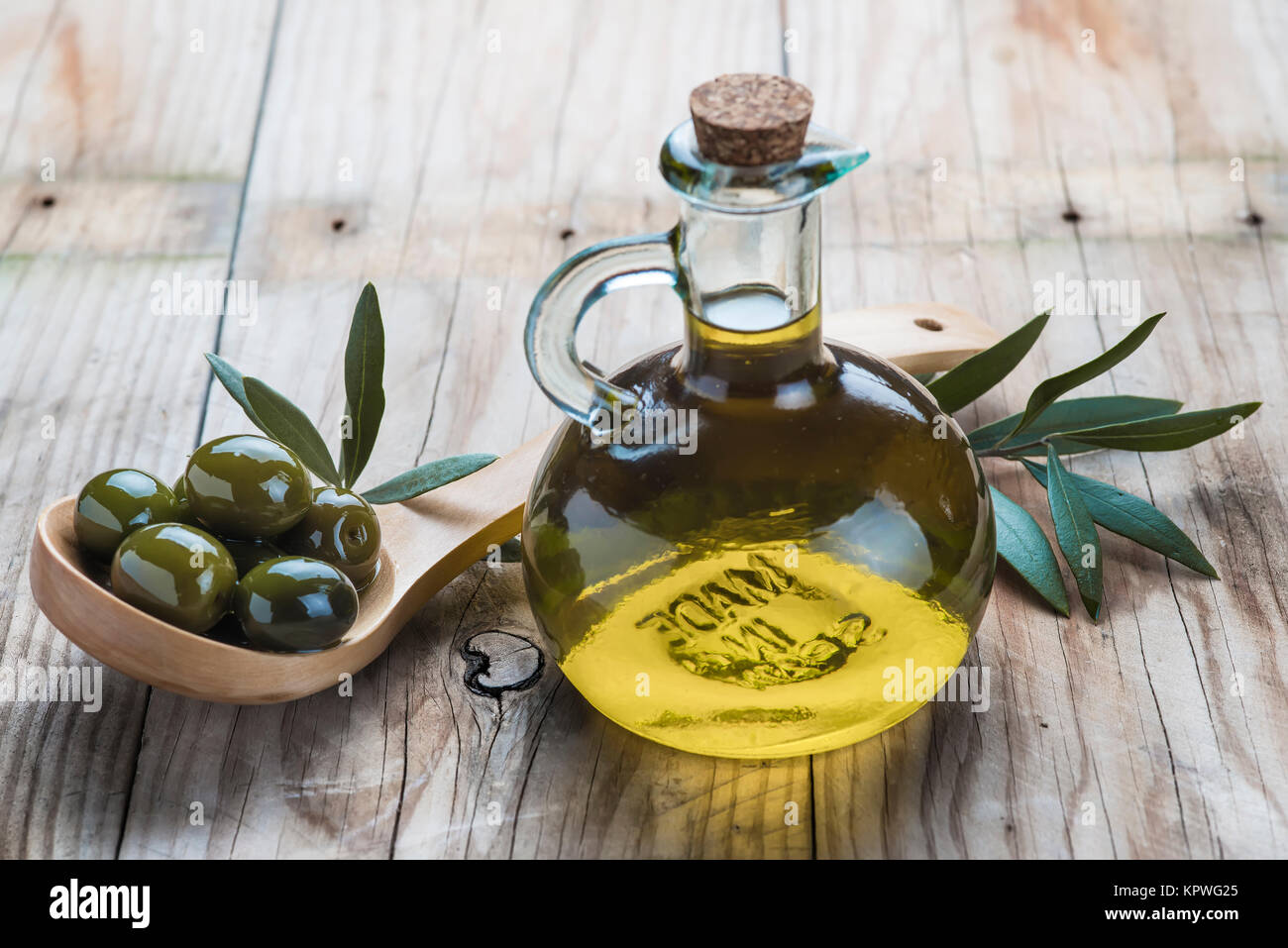 Olive oil bottle and a spoon with olives Stock Photo - Alamy