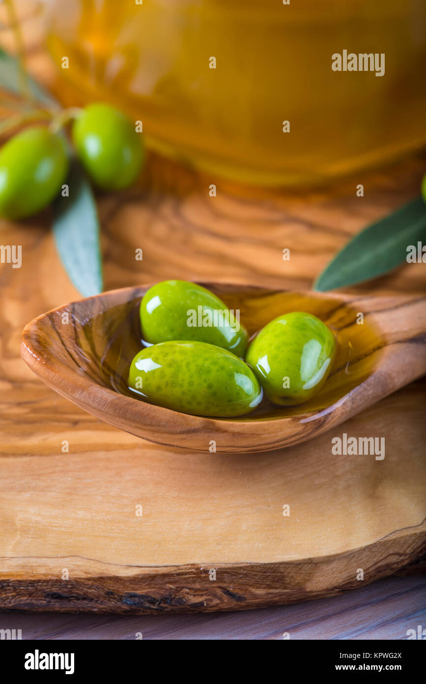 Green olives and oil on a wooden spoon Stock Photo - Alamy