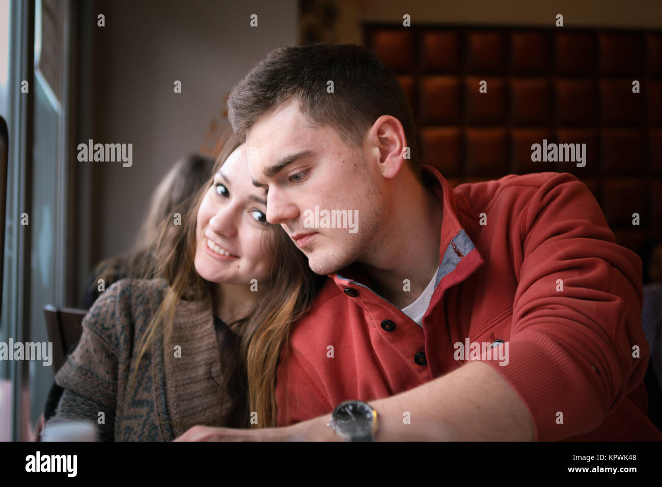 Young couple in a restaurant sitting at a table by the window and make an order. Two persons Stock Photo