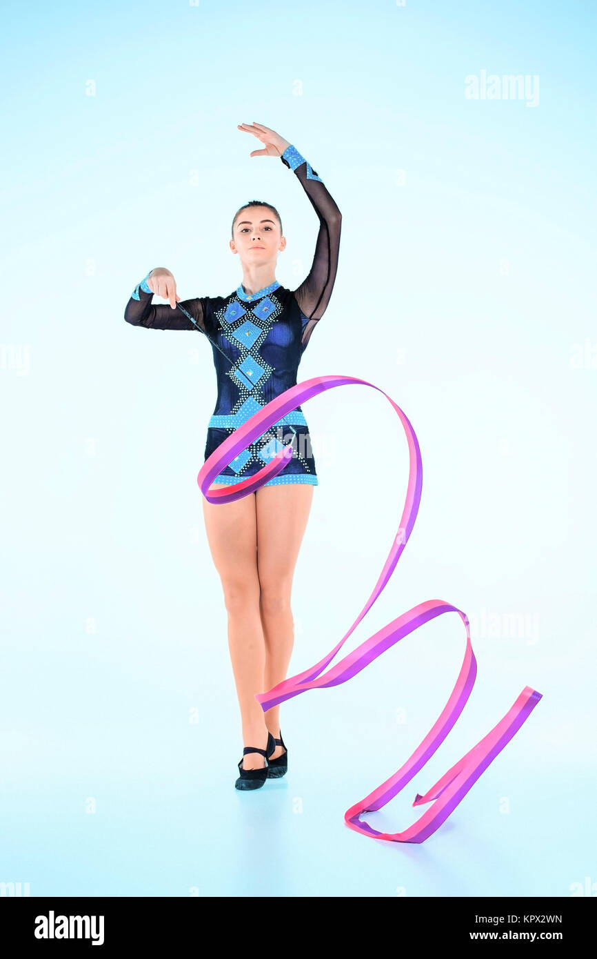 The girl doing gymnastics dance with colored ribbon on a blue background Stock Photo