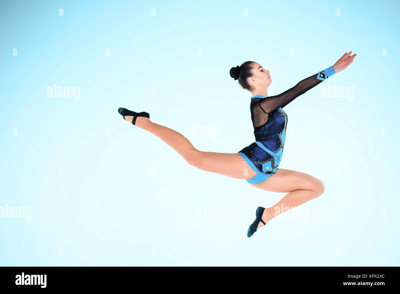 The girl doing gymnastics dance on a blue background Stock Photo