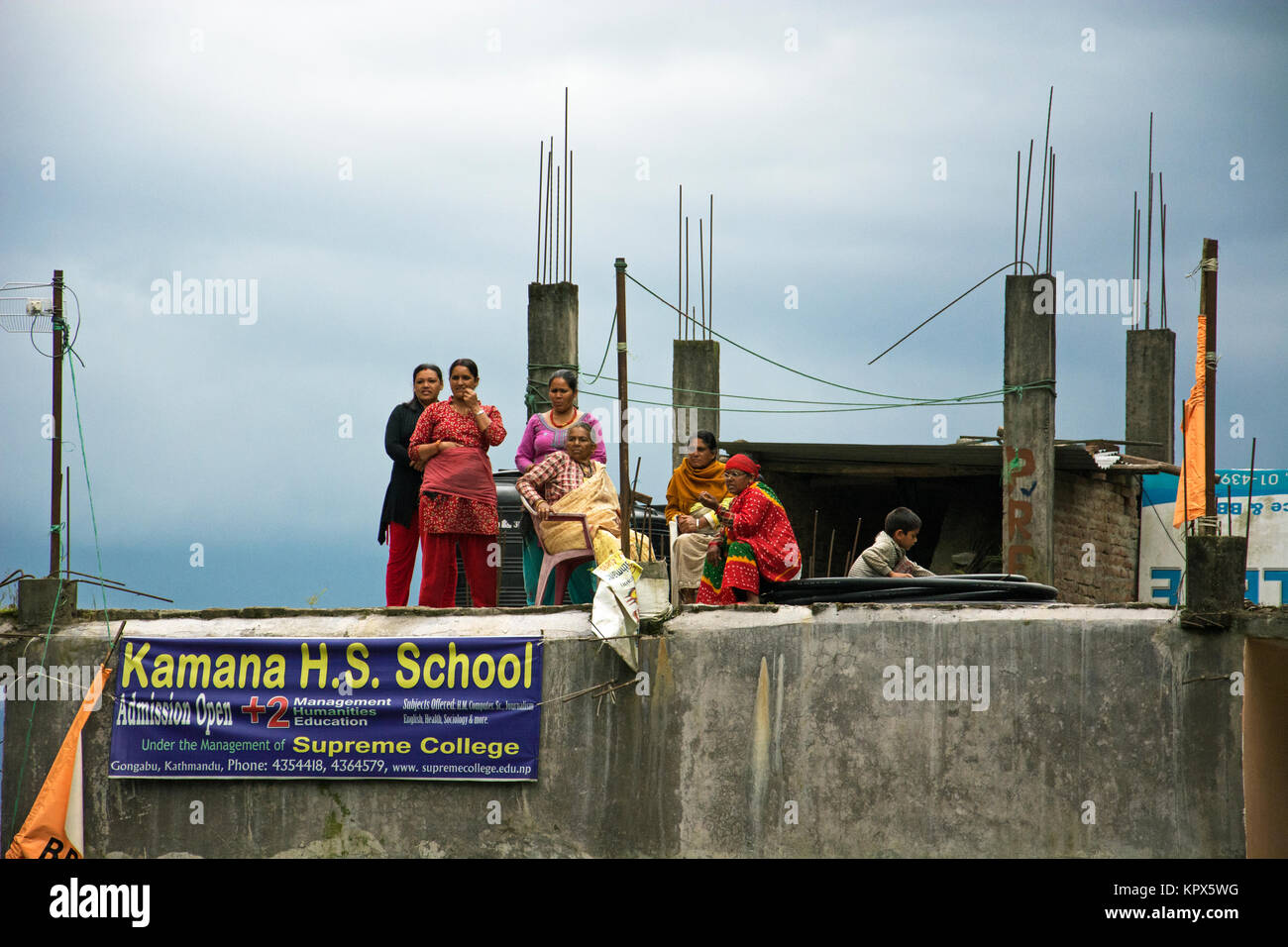 Women gathering on a rooftop to watch a political celebration/victory in a hilly mountain village just outside of Katmandu, Nepal. Stock Photo