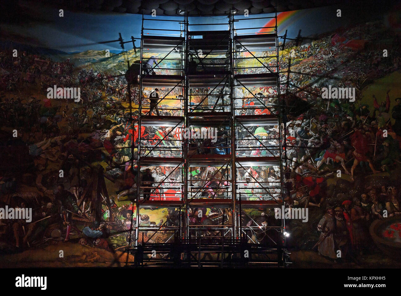 Bad Frankenhausen, Germany. 14th Dec, 2017. Conservator-restorers standing on a scaffolding cleaning a small piece of the monumental painting 'Early bourgeois revolution in Germany' by Leipzig artist Werner Tubke (1929-2004) in the Panoramuseum in Bad Frankenhausen, Germany, 14 December 2017. The 13x23 meter sized so-called Peasants' War panorama is being cleaned these days. Three conservator-restorers are clearing, using a dry specialised sponge, dust and sedimentation from the past five to six years off the face of the painting. Credit: Martin Schutt/dpa-Zentralbild/dpa/Alamy Live News Stock Photo