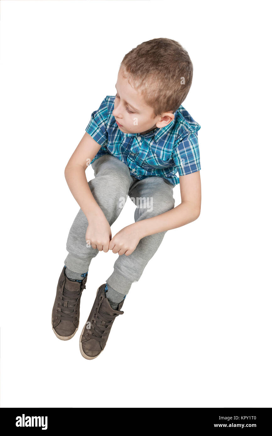 Erhöhte Ansicht auf einen neunjährigen auf Weiss freigestelten Boden Jungen nach unten blickend und ein imaginäres Seil haltend Stock Photo