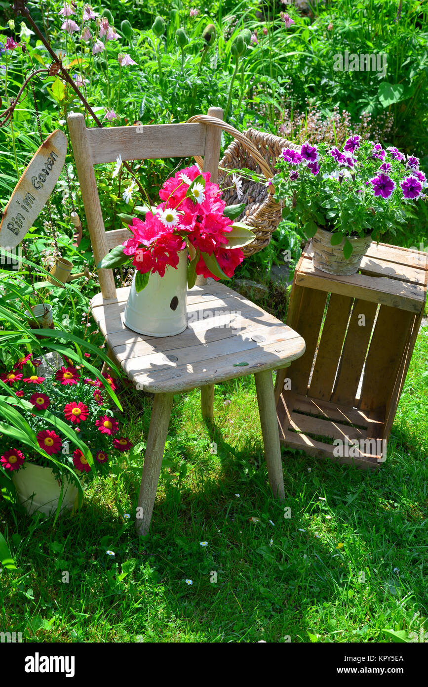 alter Stuhl im Garten mit Blumen im Frühling Stock Photo