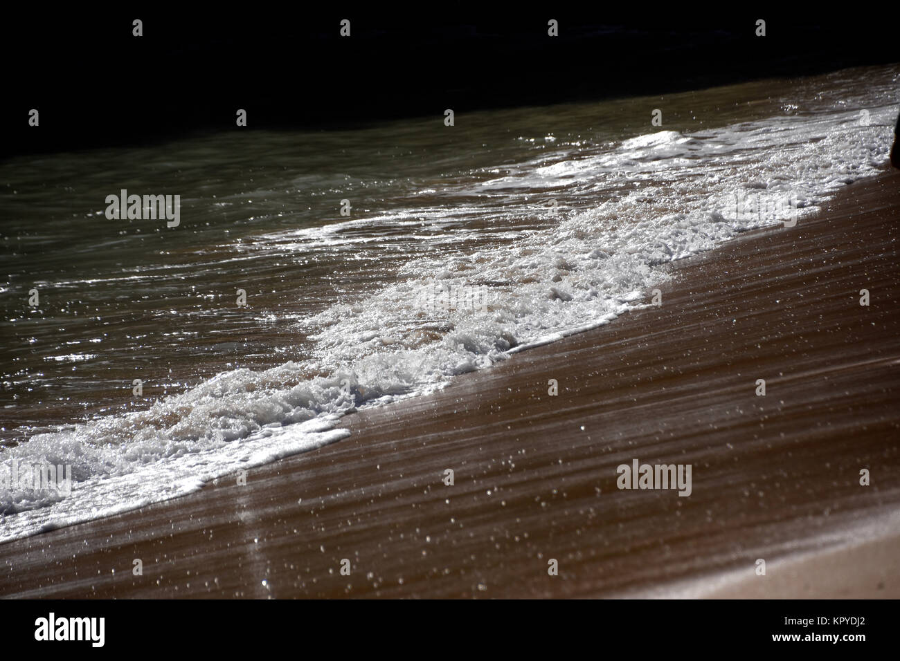 Waves and foam on the beach Stock Photo - Alamy