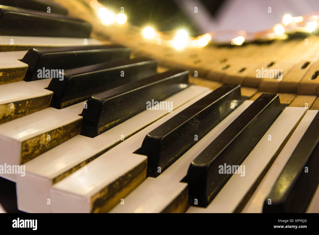 Old piano keyboard twisted with keys pushed down. Keys removed from the body of musical instrument lit up as a Christmas decoration Stock Photo
