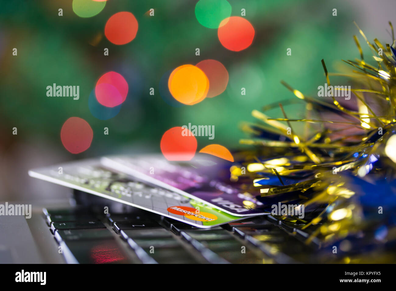 Concept image of spending at Christmas featuring credit/debit cards on a computer keyboard.Christmas tree lights in background Stock Photo