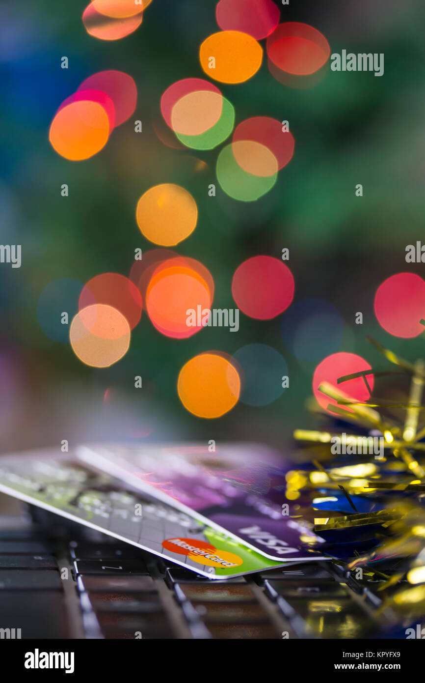 Concept image of spending at Christmas featuring credit/debit cards on a computer keyboard.Christmas tree lights in background Stock Photo