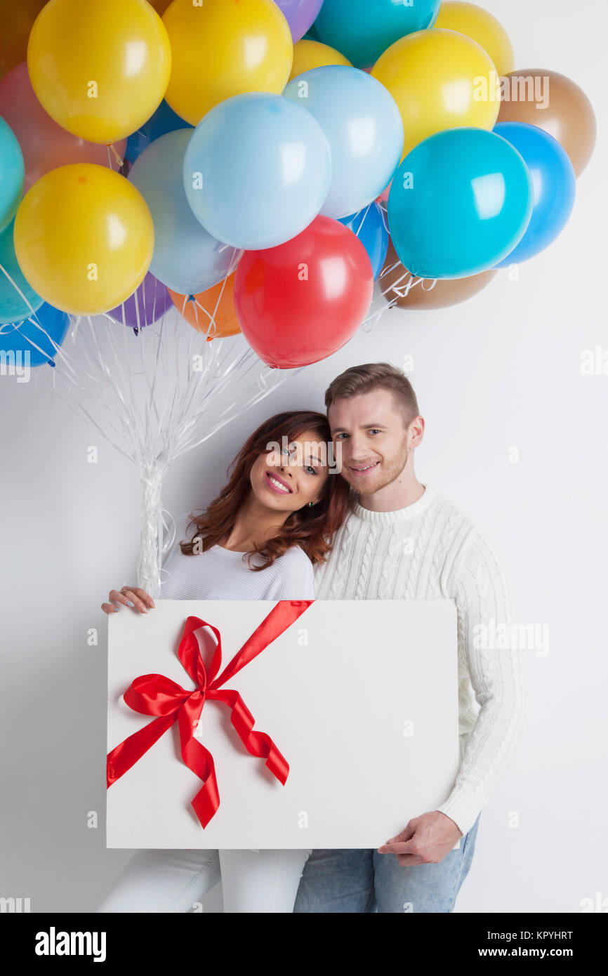 Young smiling couple with balloons and big gift box Stock Photo - Alamy