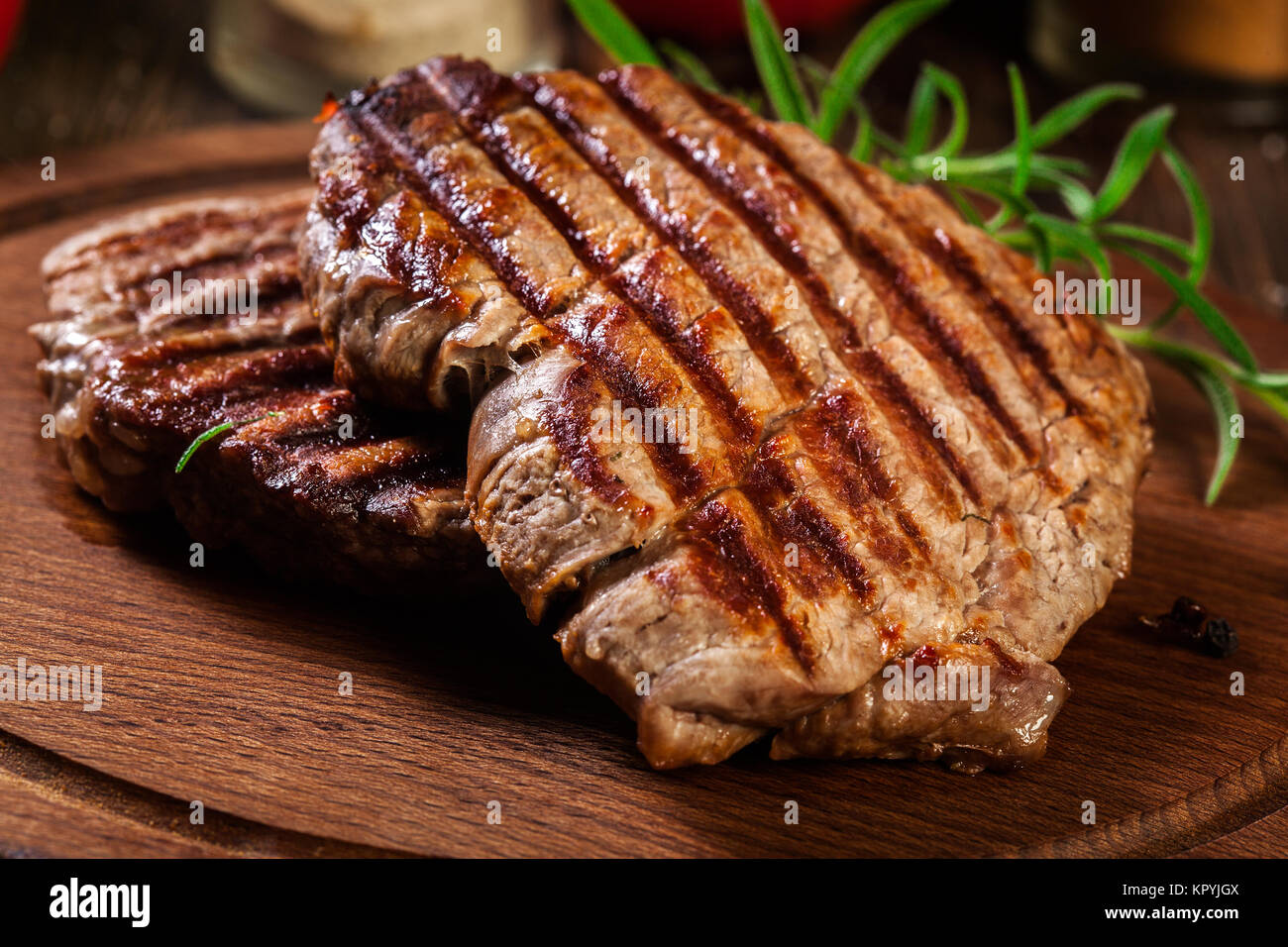 Succulent portions of grilled fillet mignon served with rosemary on an wooden board Stock Photo