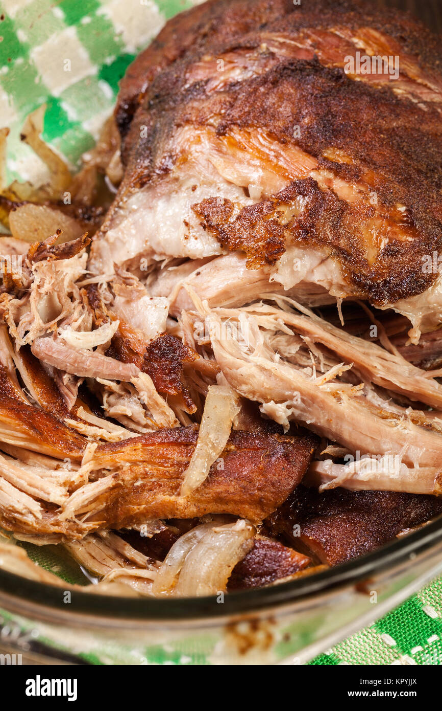 Slow cooked pulled pork shoulder with onion and garlic in casserole
