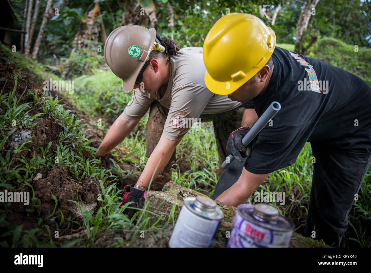 U.S. Navy Utilitiesman 1st Class Mariah Stanton, left, assigned to Naval Mobile Construction Battalion (NMCB) 133 Civic Action Team (CAT) Palau, and Roger Santos, a Palauan participating in the Apprentice Training Program, install a water catchment system at the Ngeremlengui Elementary School in Ibobang, Palau, December 13, 2017. NMCB-133 is forward deployed, providing expeditionary construction and engineering (combat service support) to include horizontal and vertical construction; maintenance and operation of expeditionary bases and facilities; tactical sustainment bridging, humanitarian as Stock Photo