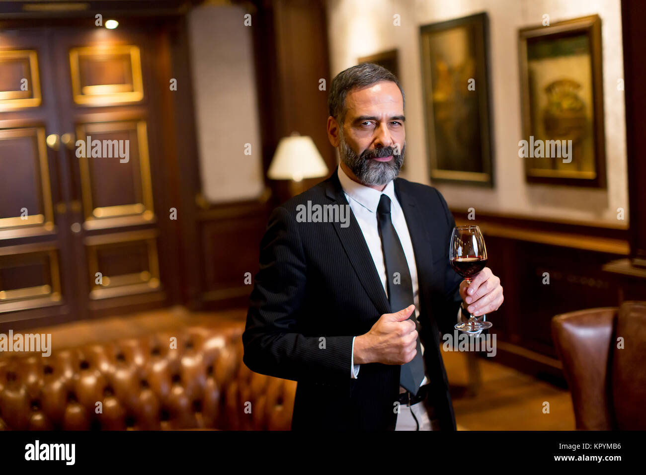 Handsome elegant businessman drinking red wine in bar Stock Photo - Alamy