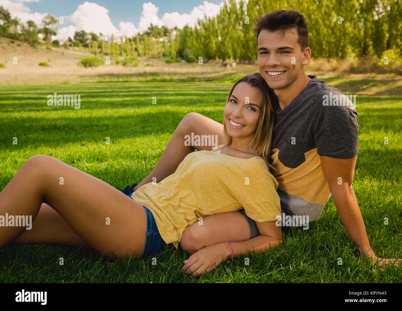 Young couple sitting on the grass and relaxing Stock Photo - Alamy