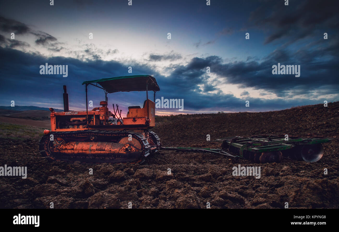 Old rusty tractor in a field on sunset.HDR image Stock Photo - Alamy