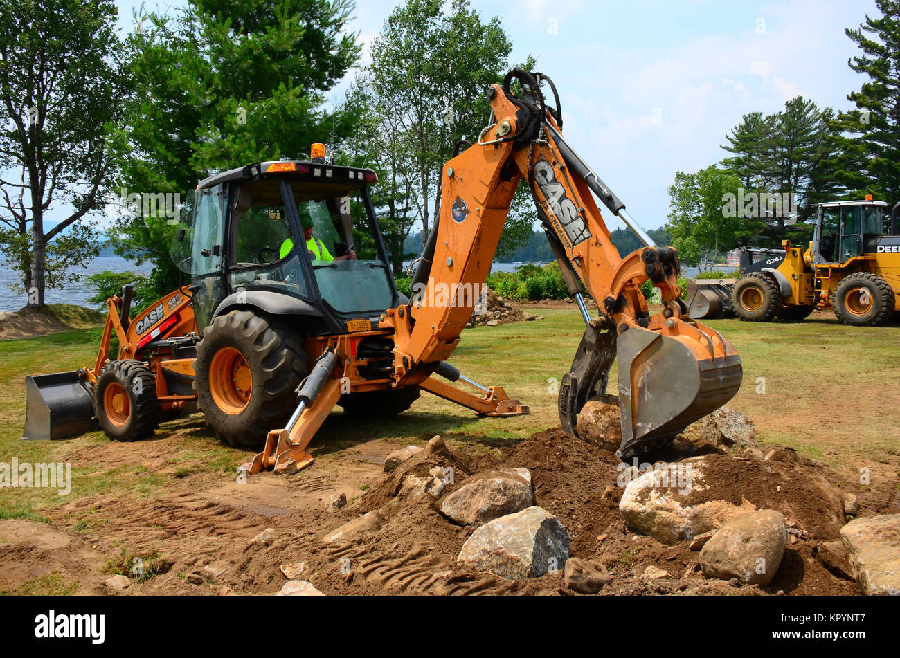 Excavator picking up boulders for placement in the Village of Speculator park on Lake Pleasant in the Adirondack Park, NY USA Stock Photo