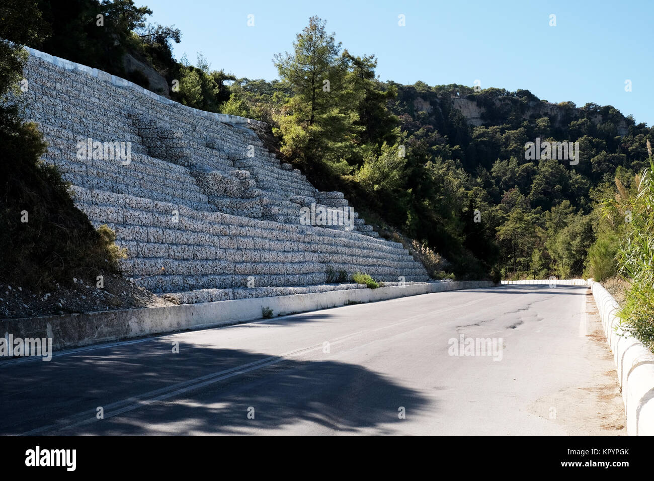A row of stepped back gabions, stone filled cages, line a mountain road protecting the embankment from erosion and protecting the road. Stock Photo