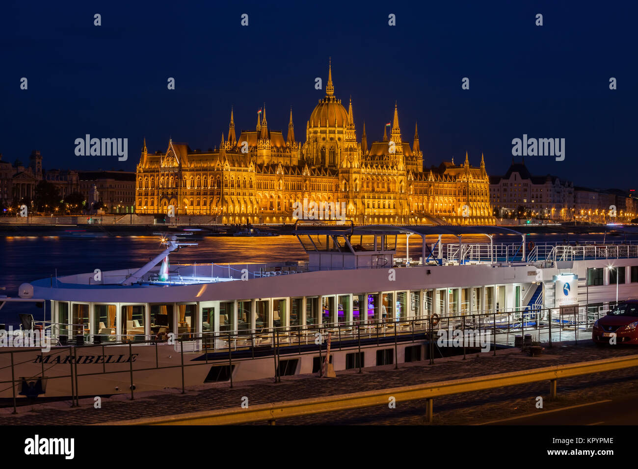 Hungary, city of Budapest, MS Maribelle OnRiver Hotel and restaurant ship with view of Hungarian Parliament Building illuminated at night Stock Photo