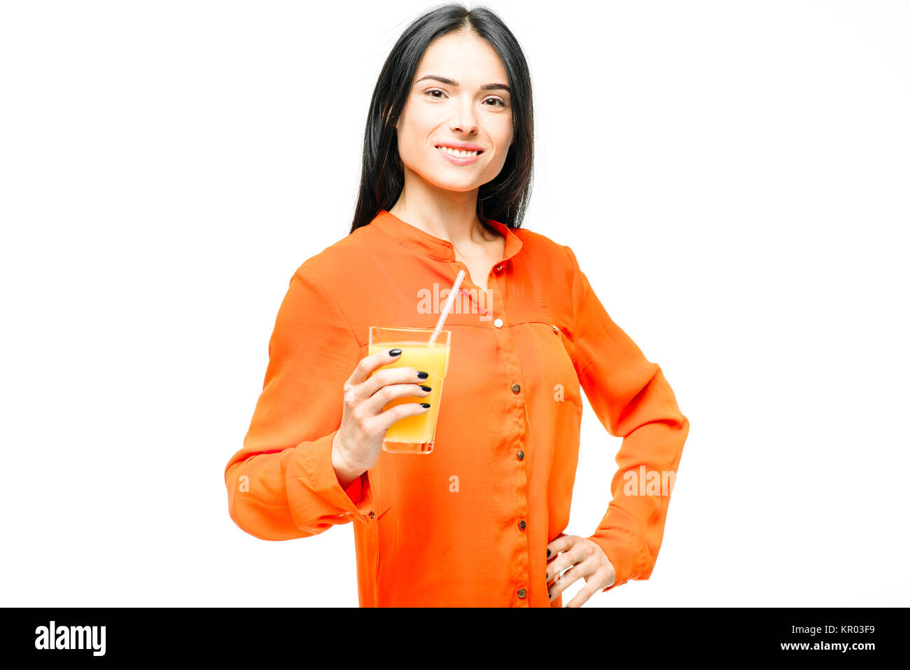 Cheerful woman in shirt and straw hat drinks freshly squeezed orange juice, white background. Young girl with yellow vitamin beverage, healthy lifesty Stock Photo