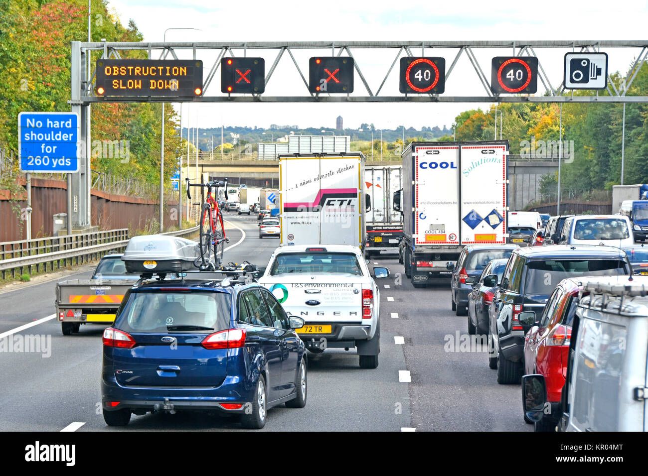 M25 motorway traffic jam signs indicate obstruction ahead two lanes closed queues as vehicles merge into two lanes Friday PM rush hour North London UK Stock Photo
