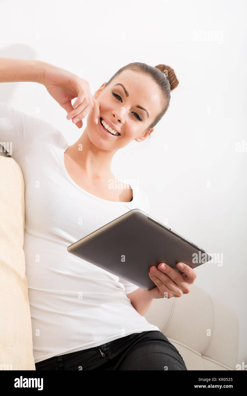 A young woman sitting on the sofa holding a tablet Stock Photo - Alamy