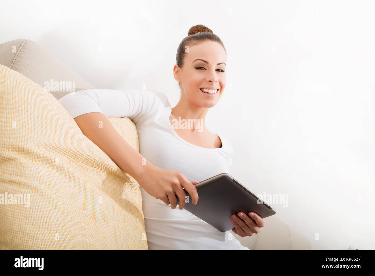 A young woman sitting on the sofa holding a tablet Stock Photo - Alamy