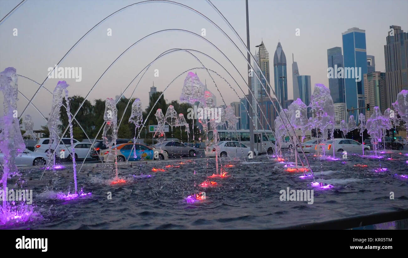 Many small splashing dancing fountains in summer Dubai park. Outdoor