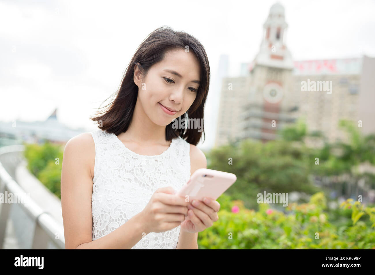 Woman using mobile phone with Hong Kong clock tower Stock Photo - Alamy