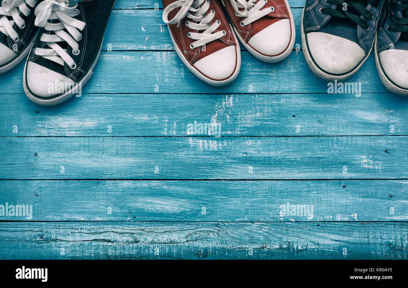 Three pairs of sneakers on a wooden blue background Stock Photo - Alamy
