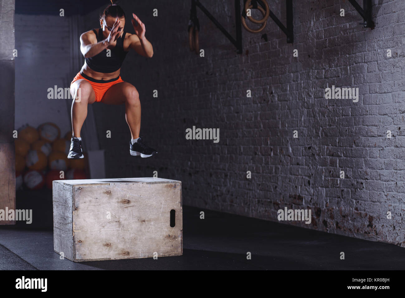 woman box jumping at cross fit gym. athlete doing box jumps exercise at
