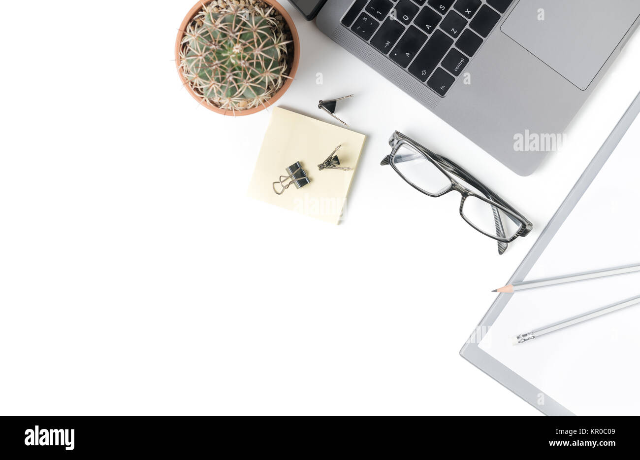 Desk with laptop, eye glasses, notebook and small cactus isolated on white background. Top view with copy space. Stock Photo