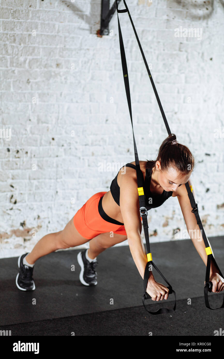 Women doing push ups training arms with trx straps in gym Stock