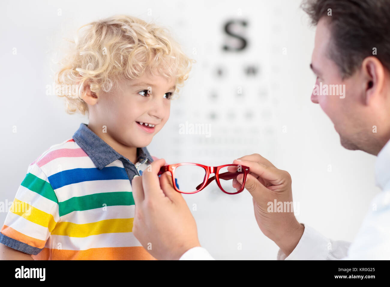 Child at eye sight test. Little kid selecting glasses at optician store