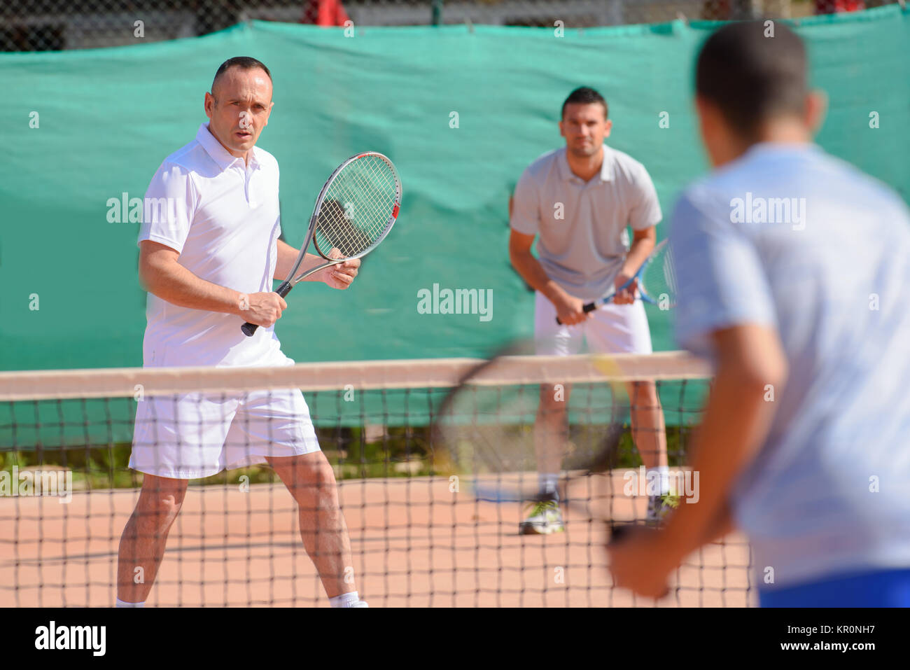 Men playing tennis doubles Stock Photo