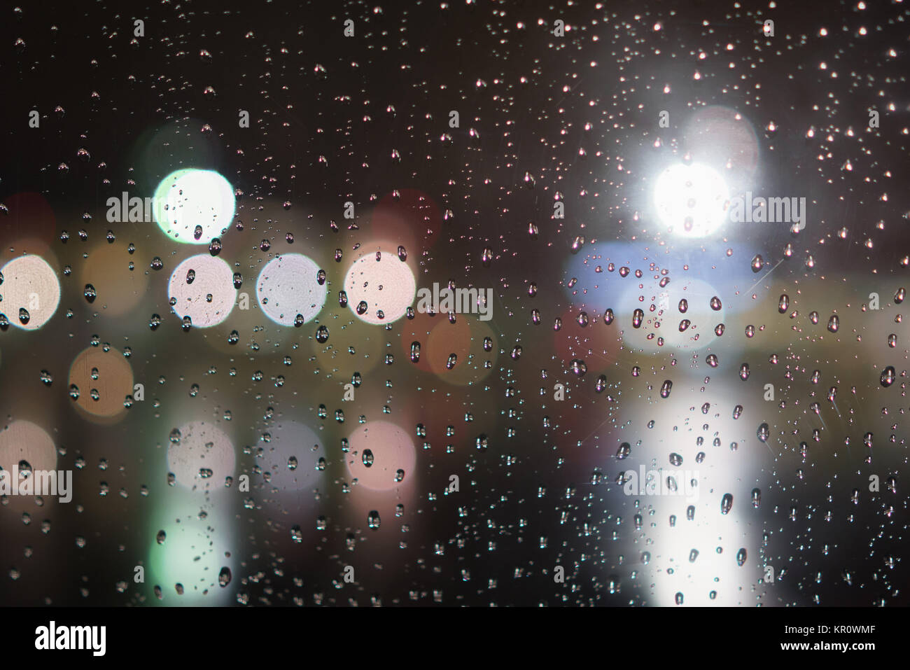 closeup of raindrops on window in night with lights, shallow focus ...