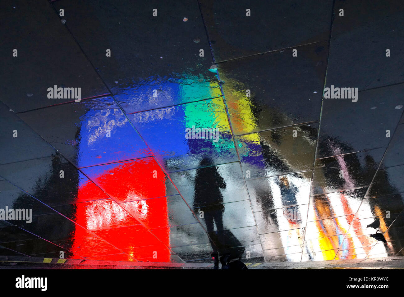Woman with suitcase photographing the night lights at Piccadilly Circus, London (reflection on a rainy day) Stock Photo