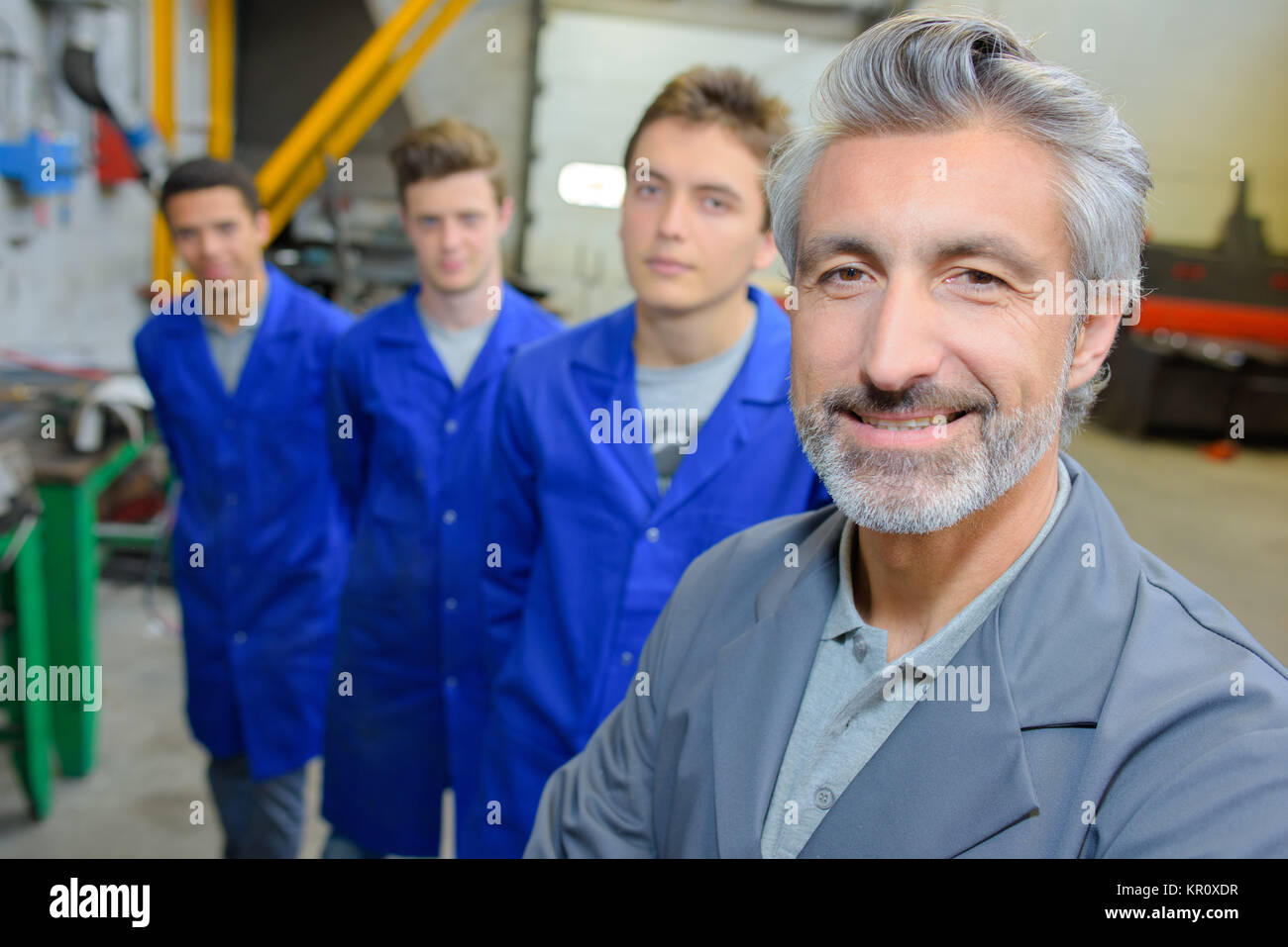 Smiling teacher with students stood behind him Stock Photo Alamy