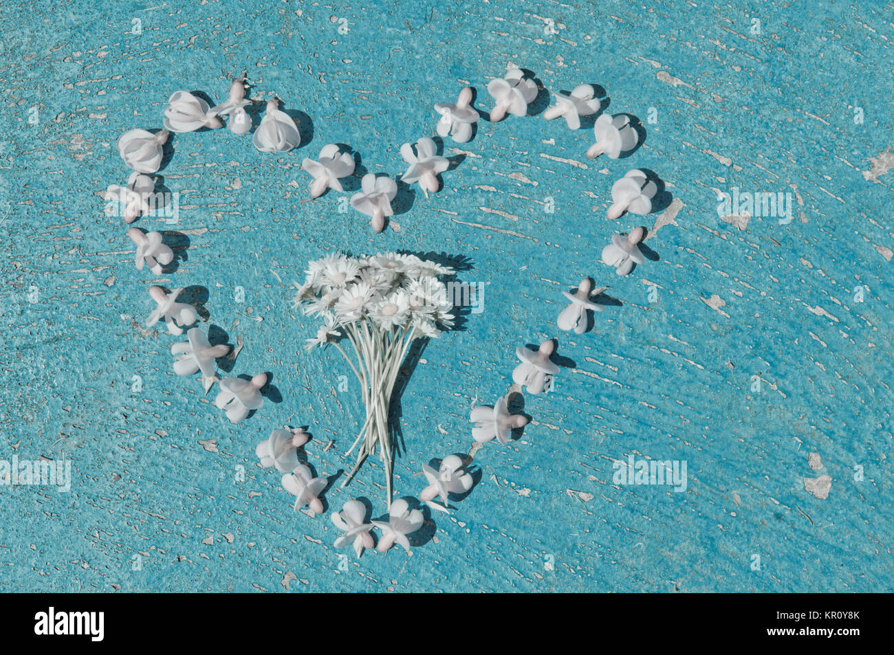 Heart shape formed from bleached flowers on an old texture light blue ...