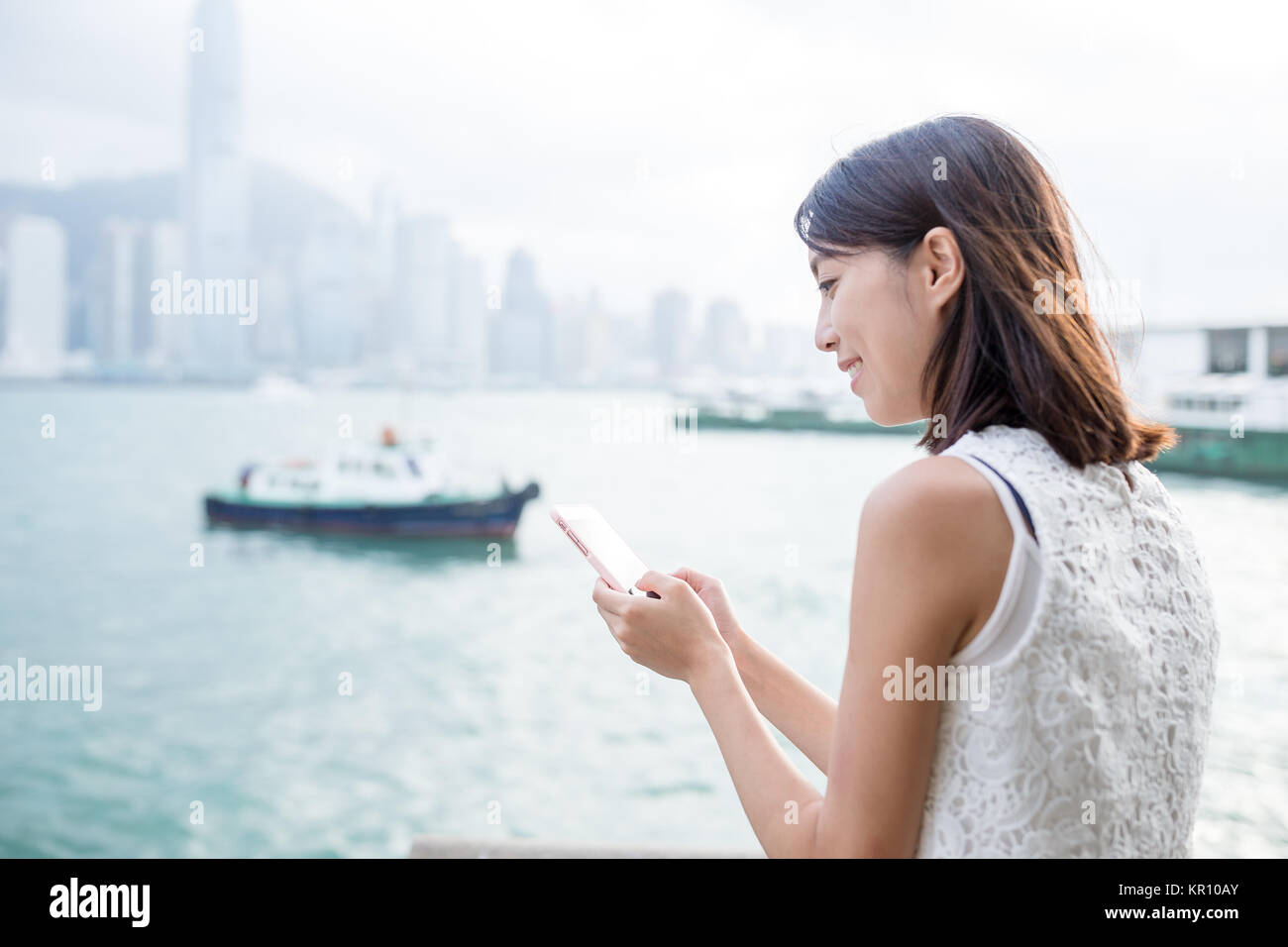 Woman using cellphone with the Hong Kong skyline Stock Photo - Alamy