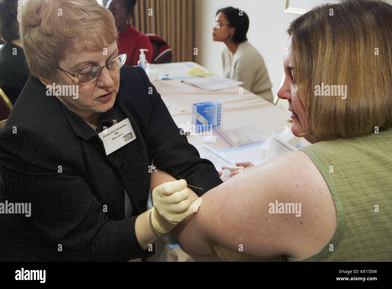Jacqueline Kowalski (Left) and Lorna Will practice proper technique with a bifurcated needle used during smallpox vaccination, 2002. In December 2002, CDC Clinicians trained state licensed vaccine administers how to deliver smallpox vaccine safely and efficiently. Once training was completed, they provided additional smallpox vaccine administration training in their home states. Image courtesy CDC. Stock Photo