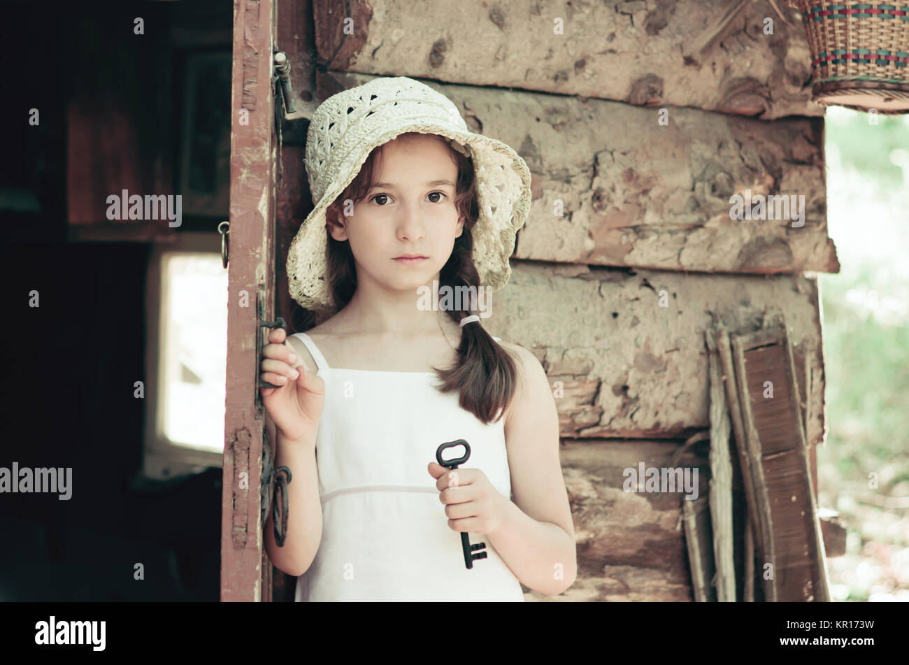 Pretty young girl standing at the door outside an old wooden hut and ...