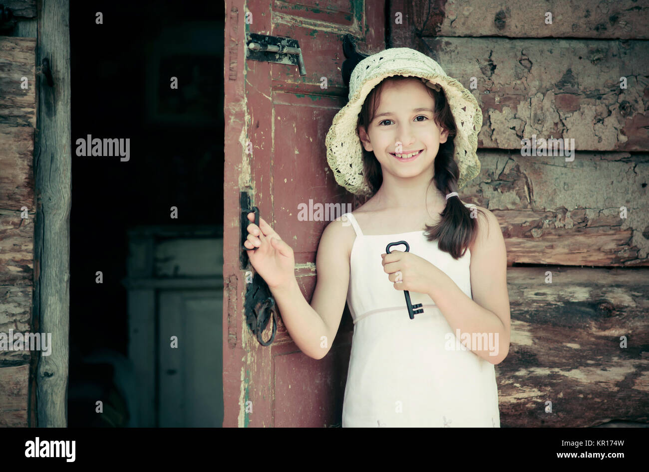 Pretty young girl standing at the door outside an old wooden hut and ...
