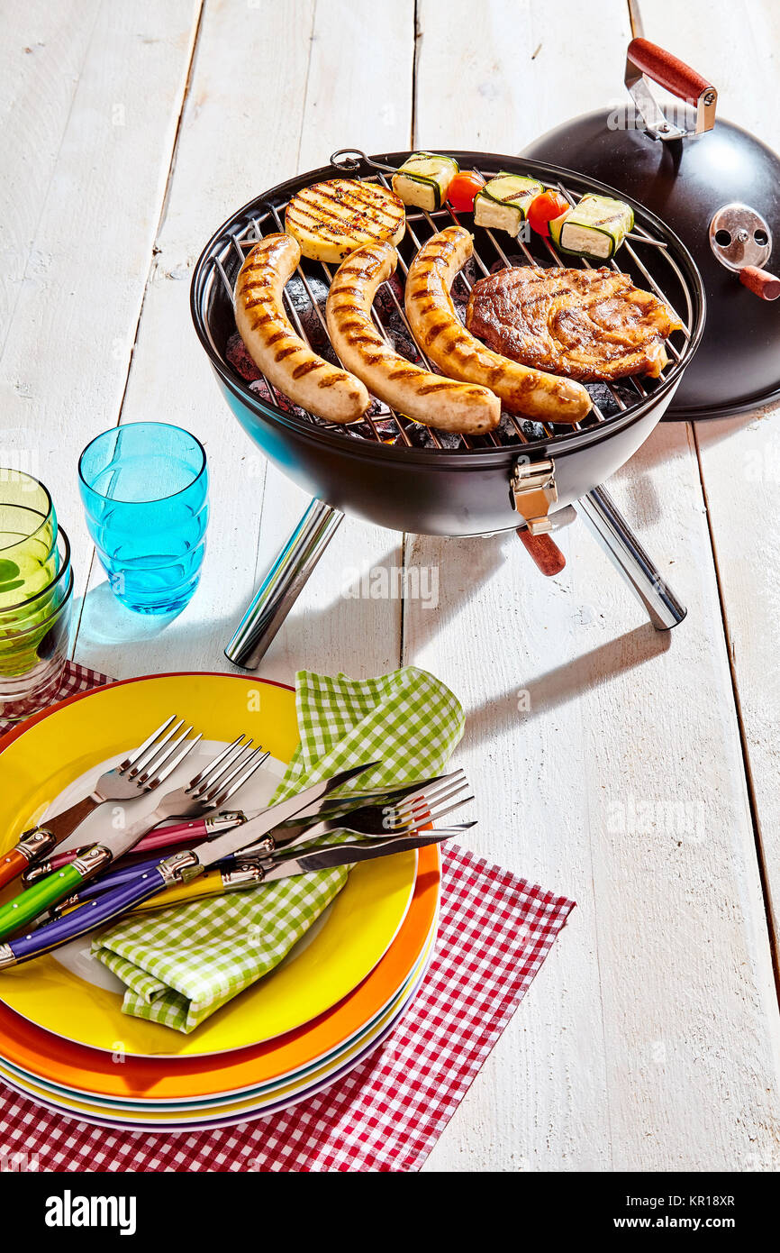 Colorful picnic plates and utensils at a barbecue on a white wooden